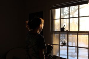 Girl by window looking at snow outside